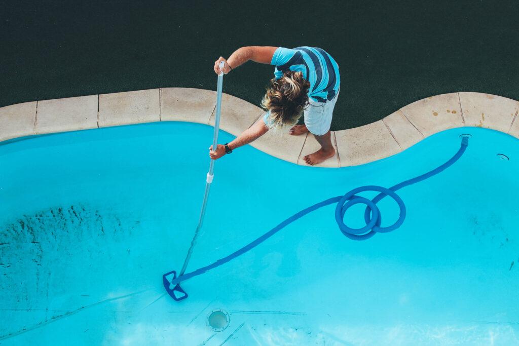 a man cleaning pool with vacuum